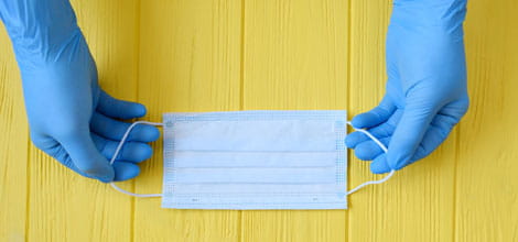 Gloved hands holding surgical mask